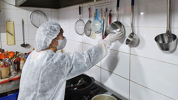 식품 위생 감시원이 한 음식점의 주방에서 위생 점검을 실시하고 있다.